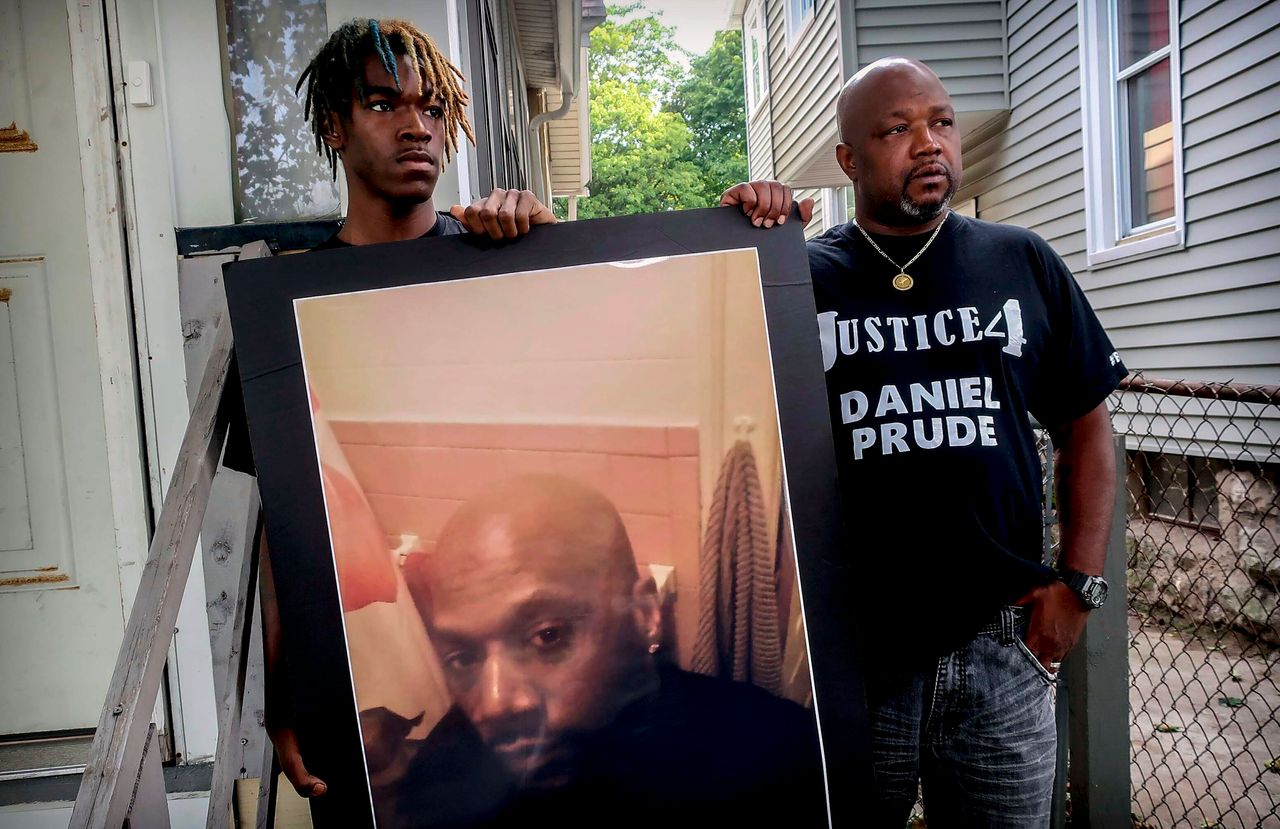 Armin Prude (left) and Joe Prude hold an enlarged photo of Daniel Prude on Sept. 3, 2020. Daniel Prude died following a police encounter in Rochester, New York. City officials have agreed to pay $12 million to the family of Daniel Prude, a Black man who died after police held him down until he stopped breathing after encountering him running naked through the snowy streets of Rochester.