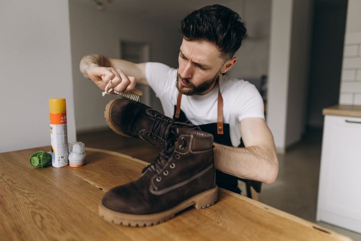 Man cleans boots with a brush and cleaning products