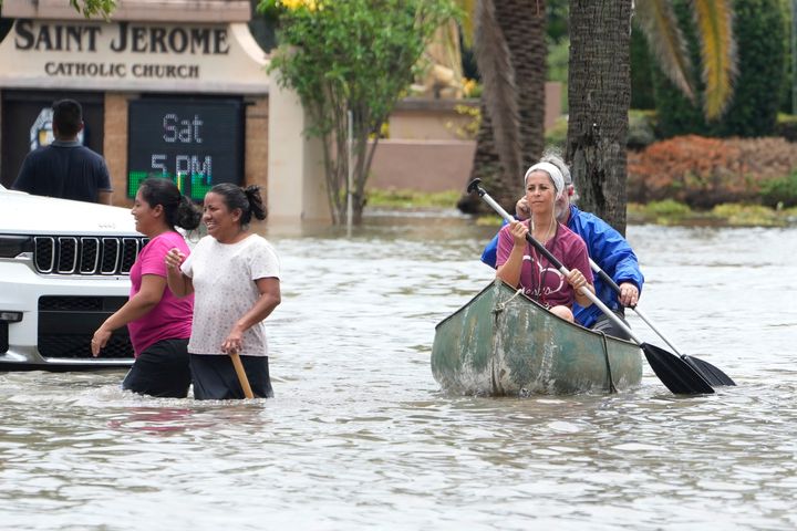 Residents paddle and walk along a flooded road April 13, 2023, in Fort Lauderdale, Fla. Over two feet of rain fell causing widespread flooding, closing the Fort Lauderdale airport and turning thoroughfares into rivers. 