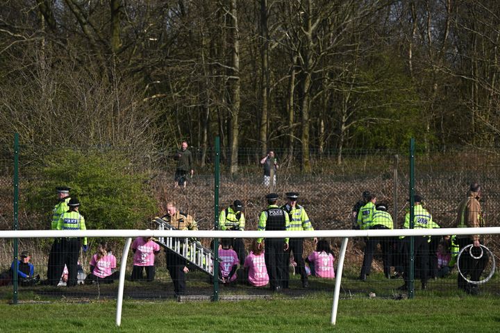 Animal rights protesters are apprehended by police officers behind the fence ahead of the Grand National Handicap Steeple Chase