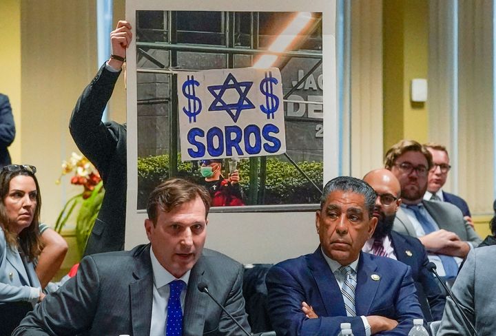 Rep. Dan Goldman (D-N.Y.) has an aide display an image of a demonstrator carrying a sign about philanthropist George Soros outside the site of the House Judiciary Committee field hearing in New York City. He ripped Republicans for making antisemitism a feature of their political attacks on Manhattan District Attorney Alvin Bragg.