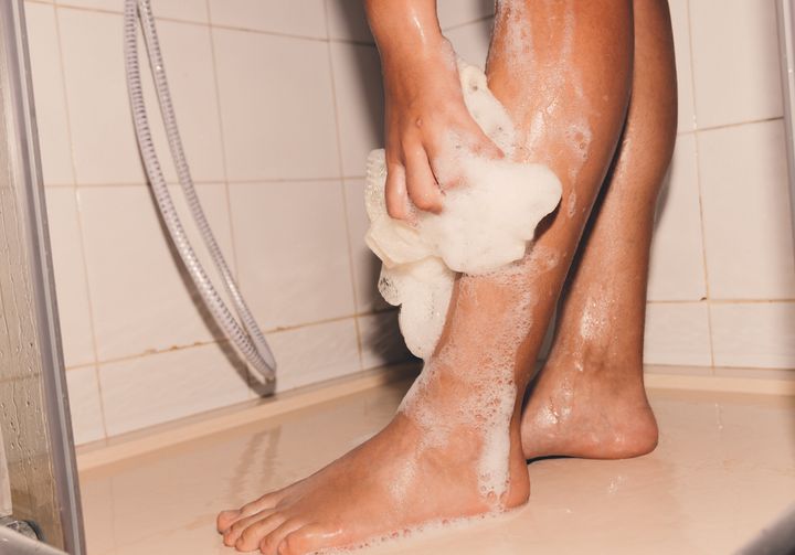 Woman washing her legs with gel in the shower