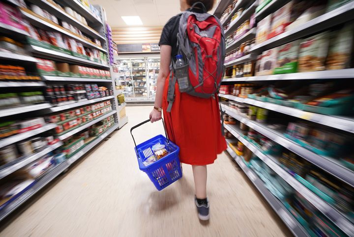 A shopper walking through the aisle of a Tesco supermarket as food inflation continues to go up.