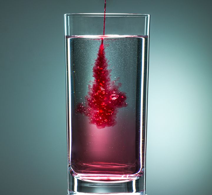 Red liquid being squirted into drinking glass