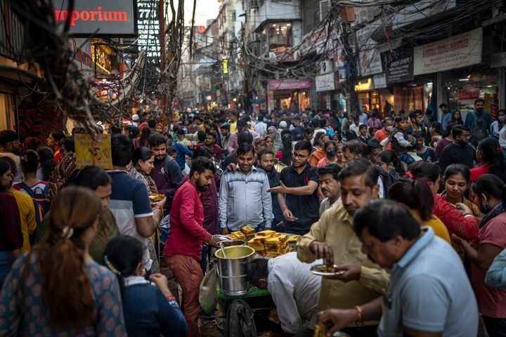 FILE-People eat street food as shoppers crowd a market in New Delhi, India, Saturday, Nov. 12, 2022. The world's population is projected to hit an estimated 8 billion people on Tuesday, Nov. 15, according to a United Nations projection. India is on track to become the world's most populous nation, surpassing China by 2.9 million people by mid-2023, according to data released by the United Nations on Wednesday. The South Asian country will have an estimated 1.4286 billion people against China's 1.4257 billion by the middle of the year, according to U.N. projections.(AP Photo/Altaf Qadri, File)