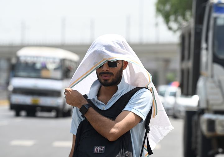 Ένας νεαρός καλύπτει το κεφάλι του με πετσέτα για να προστατευτεί από το σοβαρό κύμα καύσωνα στον τομέα 38 στις 18 Απριλίου 2023 στη Νόιντα της Ινδίας.