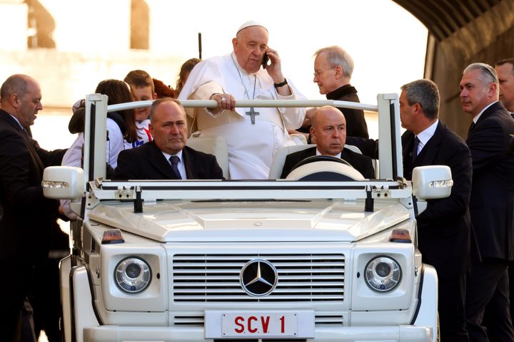 Pope Francis talks on the phone as he arrives at St Peter's Square for his weekly general audience in Vatican City.