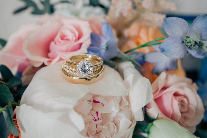 A moissanite engagement ring sits atop a stack of rings.