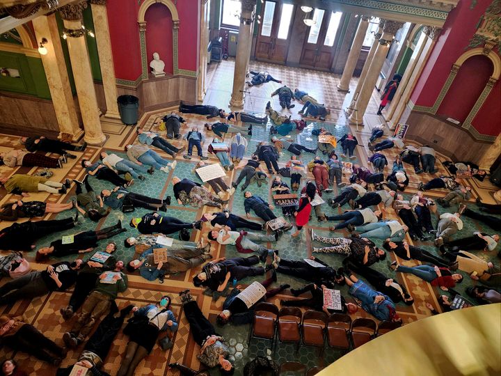 Attendees of the Transgender Day of Visibility rally in Montana lay down on the floor in the state Capitol rotunda in an event inspired by "die-ins" held by AIDS activists in the 1980s, Friday, March 31, 2023 in Helena, Mont. The effort was to "visibly lay our bodies in this space and claim this space as our own," said Izzi Milch, senior advocacy manager with Forward Montana, a nonprofit dedicated to helping younger residents to get engaged in politics and shape policies. A performer, who goes by the name Natalita, led participants in a chant saying: "My body is my own. I am in control." 
