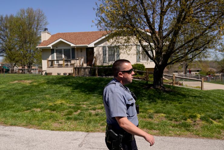 A police officer walks past the house where 16-year-old Ralph Yarl was shot April 13 when he went to the wrong address in Kansas City, Mo., to pick up his younger brothers.