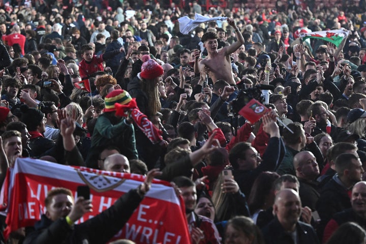 Wrexham's fans celebrate on the pitch after the English National League football match between Wrexham and Boreham Wood at the Racecourse Ground Stadium in Wrexham, north Wales, on April 22, 2023. - Hollywood stars Ryan Reynolds and Rob McElhenney embraced in celebration as they watched Wrexham, who the duo bought in 2020, reach the English Football League for the first time in 15 years on Saturday after a 3-1 win over Boreham Wood. (Photo by Oli SCARFF / AFP) (Photo by OLI SCARFF/AFP via Getty Images)