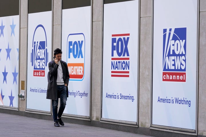 FILE – A man walks past the News Corp. and Fox News headquarters on Wednesday in New York. Fox Corp.'s hefty $787.5 million settlement with Dominion over defamation charges is unlikely to make a dent in Fox's operations, analysts say.