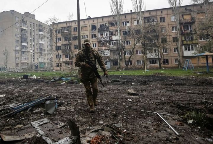 A Ukrainian service member walks near residential buildings damaged by a Russian military strike, amid Russia's attack on Ukraine.