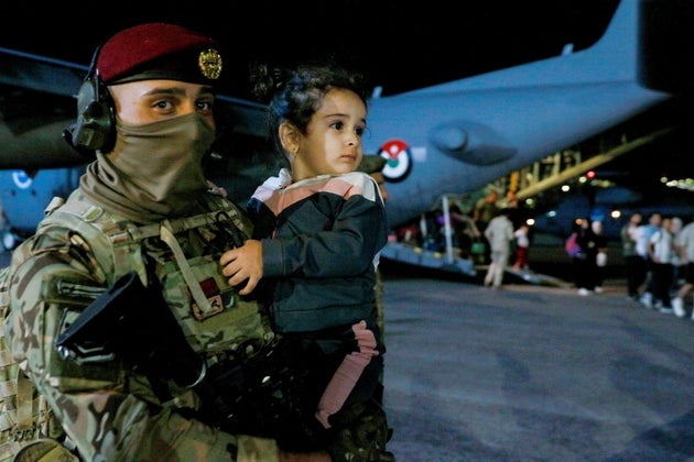 A soldier carries a child as people evacuated from Sudan disembark from an aircraft at a military airport in Amman on April 24, 2023.