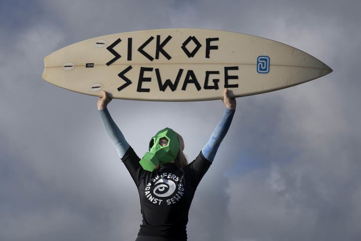 A representative from Surfers against Sewage protests against sewage discharges at an overflow pipe on Long Rock Beach in Penzance, Cornwall.