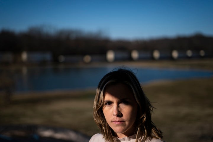 Jessica Conard poses for a photograph as a train roles by her home in East Palestine, Ohio, Tuesday, March 7, 2023. She wonders after the train derailment if her kids will ever be able to fish in the pond separating their property from the railroad tracks. Or play at the park where the chemicals are being removed from a stream. Can they remain in the town where "generations upon generations" of family have lived?