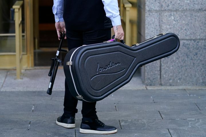 Um membro da comitiva do artista Ed Sheeran carrega um estojo de guitarra antes de Sheeran deixar o Tribunal Federal de Nova York, já que os procedimentos são suspensos por um dia em seu julgamento por violação de direitos autorais, em 26 de abril de 2023, em Nova York.