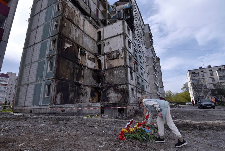 UMAN, UKRAINE - 2023/04/30: Woman lays flowers in front of a destroyed apartment building that was damaged as a result of a missile attack by the Russian army in the city of Uman. (Photo by Sergei Chuzavkov/SOPA Images/LightRocket via Getty Images)