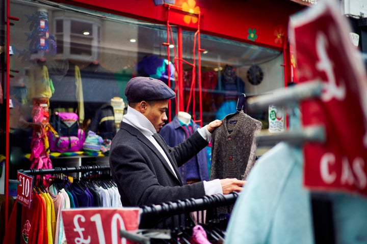 Couple looking through second hand clothing rails and having fun in Brighton in the UK