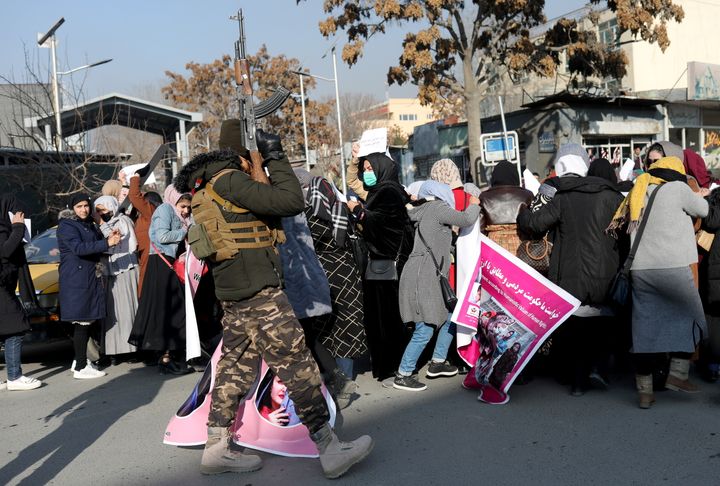 A member of Taliban fires in the air to disperse the Afghan women during a rally to protest against Taliban restrictions on women, in Kabul, Afghanistan, Dec. 28, 2021.