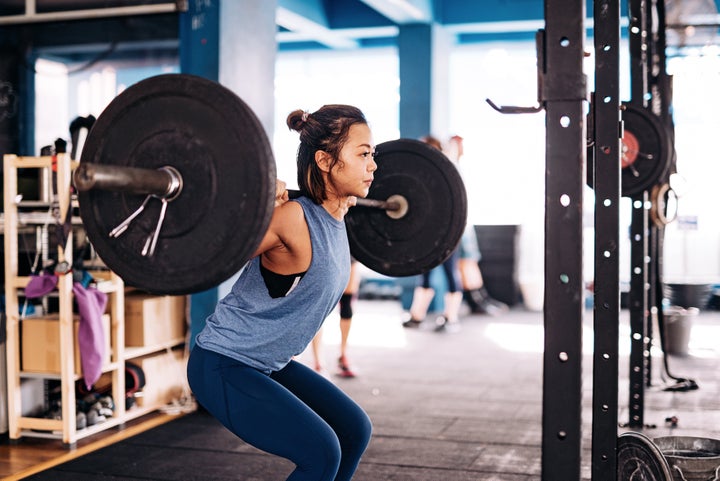 Personal trainer helping girl making excercise in gym Stock Photo