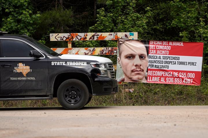 A Texas State Trooper vehicle passes a wanted poster for a suspect in the mass shooting in Cleveland, Texas.