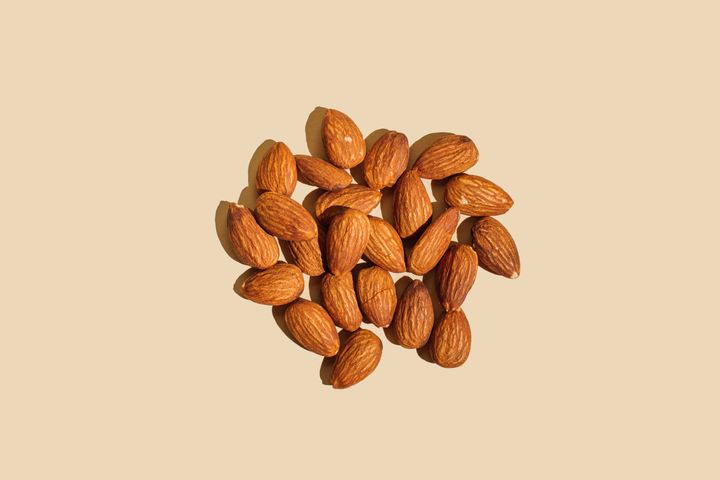 Close-up of almond nuts isolated on beige background. Healthy eating concept. Top view, flat lay.