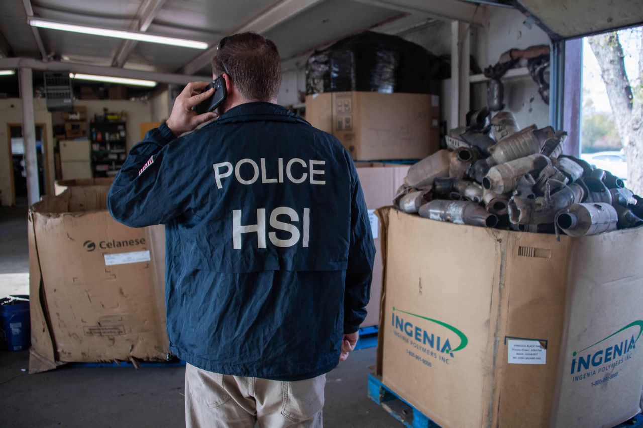An officer with Homeland Security Investigations with a box of seized catalytic converters as part of Operation Heavy Metal.