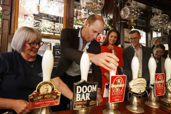 Prince William pulls the first pint of Kingmaker, a new brew celebrating the coronation of King Charles III, as he and the Princess of Wales visit the Dog & Duck pub in London on May 4, 2023, to hear how it's preparing for the coronation of King Charles III and the Queen Consort at the weekend.