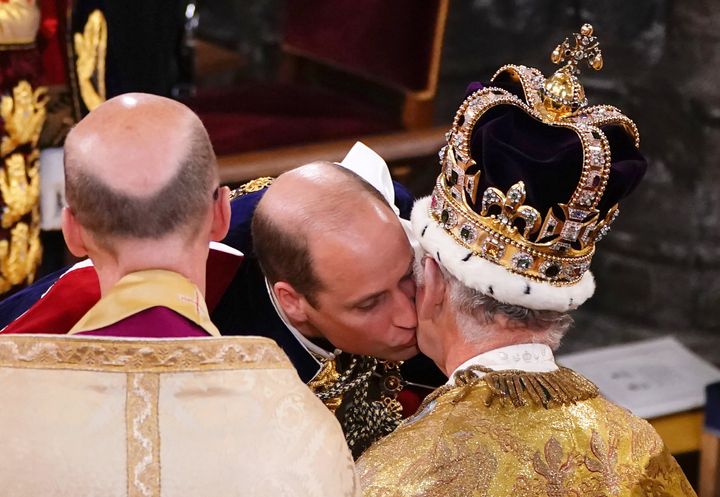 Prince William, Prince of Wales kisses his father, King Charles III, wearing St Edward's Crown, during the King's Coronation Ceremony.