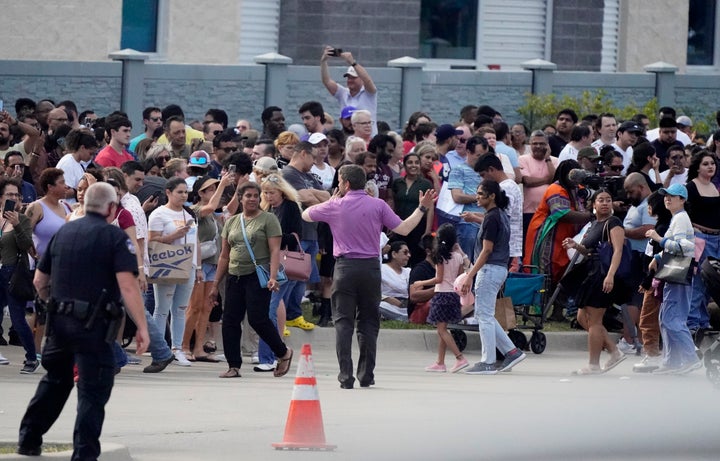 People gather across the street from the shopping center in Allen, Texas on Saturday. Republican Texas Gov. Greg Abbott, who has signed laws easing firearms restrictions following past mass shootings, called it an “unspeakable tragedy.”