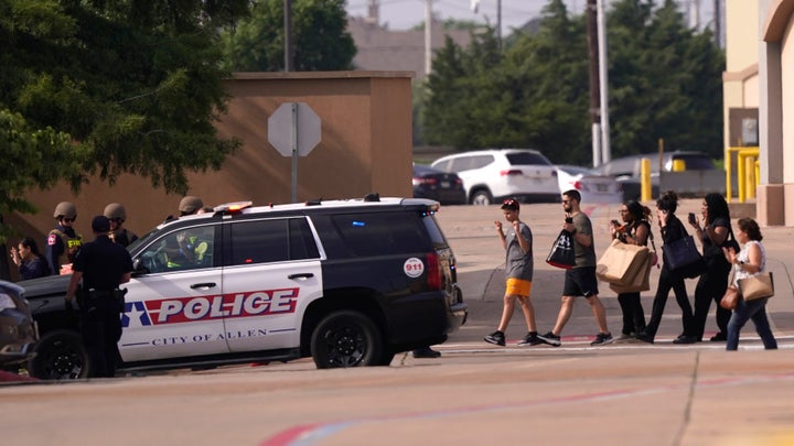 People raise their hands as they leave the shopping center in Allen, Texas on Saturday. Dashcam video that circulated online showed the gunman getting out of a car and shooting at people on the sidewalk. More than three dozen shots could be heard as the vehicle recording the video drove off.