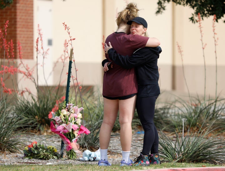 Une mère et sa fille s'embrassent dimanche où des fleurs ont été laissées sur les lieux d'une fusillade la veille à Allen Premium Outlets.