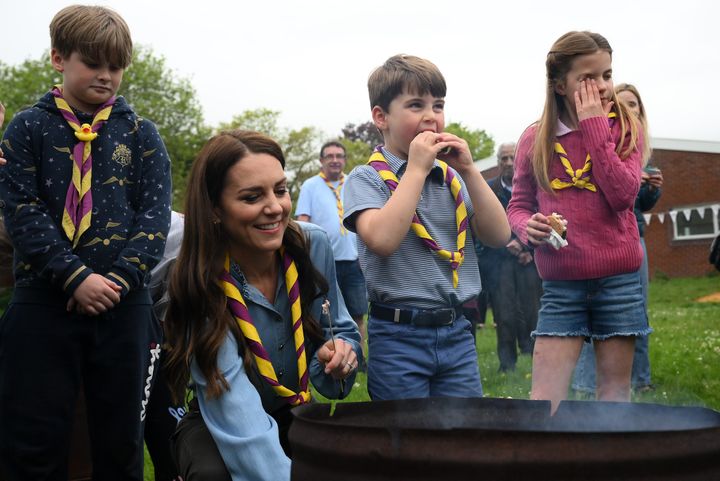 Princess Charlotte rubs her eyes as Prince Louis and Kate, Princess of Wales, toast marshmallows during the Big Help Out.