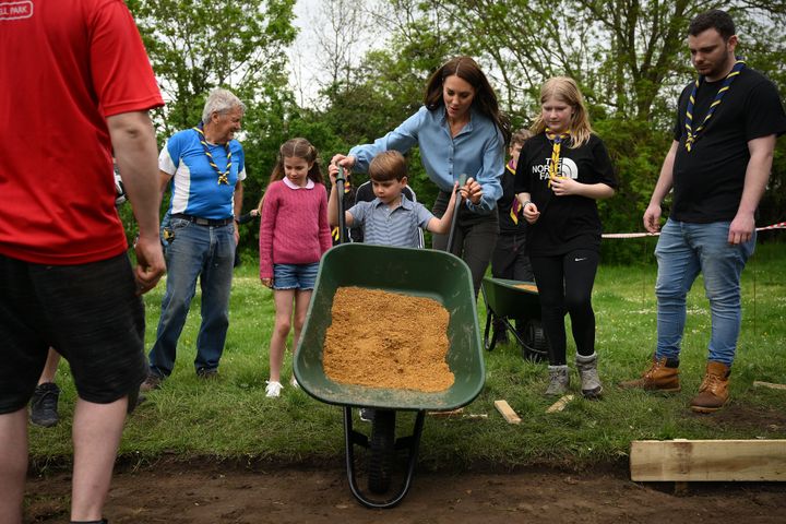 Prince Louis helps his mum push a wheelbarrow.