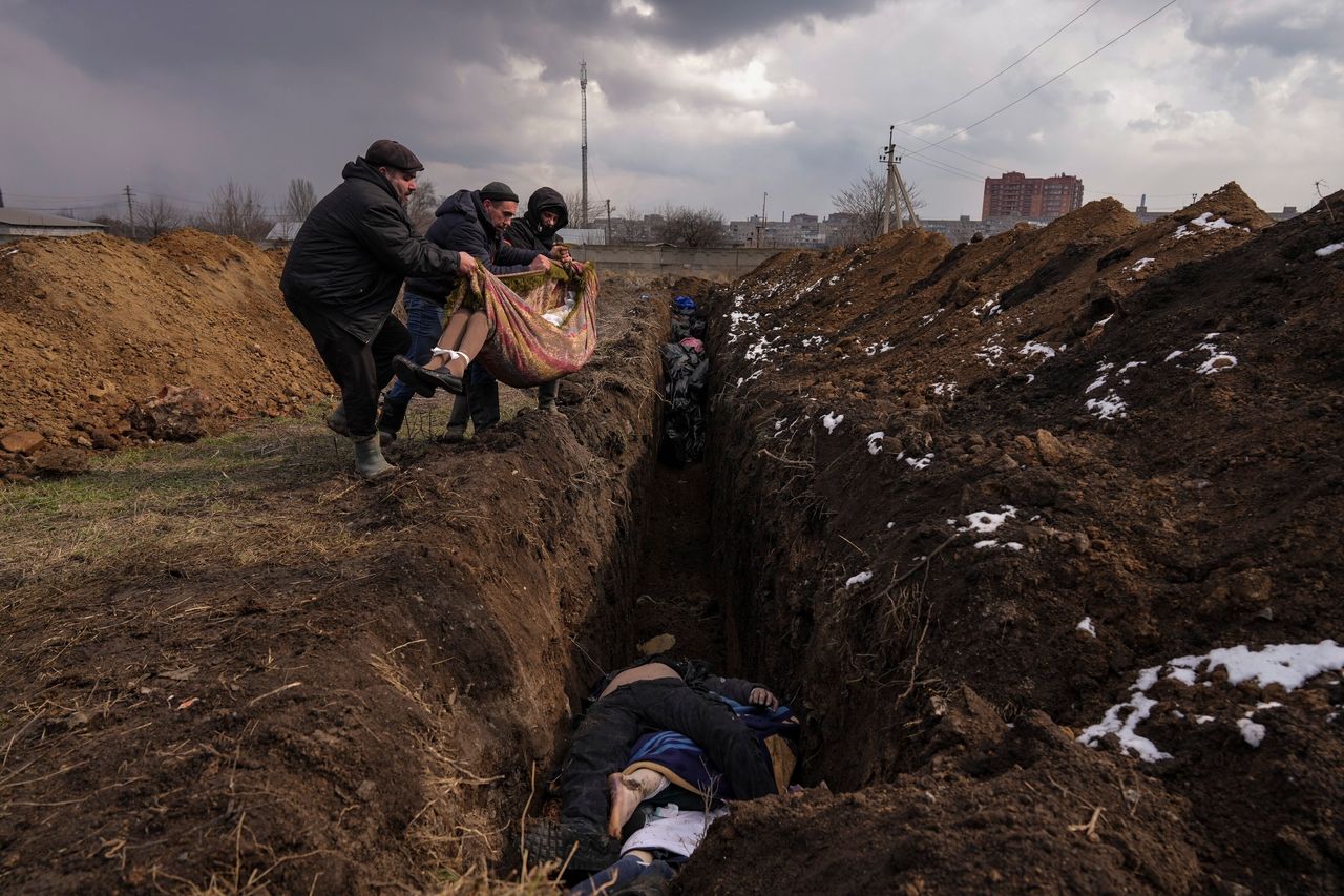 Τα πτώματα τοποθετούνται σε έναν ομαδικό τάφο στα περίχωρα της Μαριούπολης, Ουκρανία, 9 Μαρτίου 2022. Η εικόνα ήταν μέρος μιας σειράς εικόνων από φωτογράφους του Associated Press που τιμήθηκαν με το βραβείο Πούλιτζερ 2023 για τη φωτογραφία έκτακτων ειδήσεων. (AP Photo/Evgeniy Maloletka)