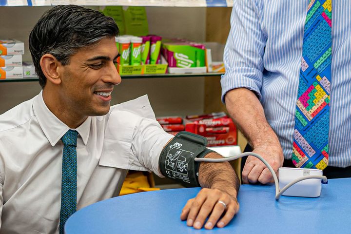 Britain's Prime Minister Rishi Sunak reacts as he has his blood pressure checked by pharmacist Peter Baillie, during a visit to a GP surgery and pharmacy in Weston, southern England on May 9, 2023. 