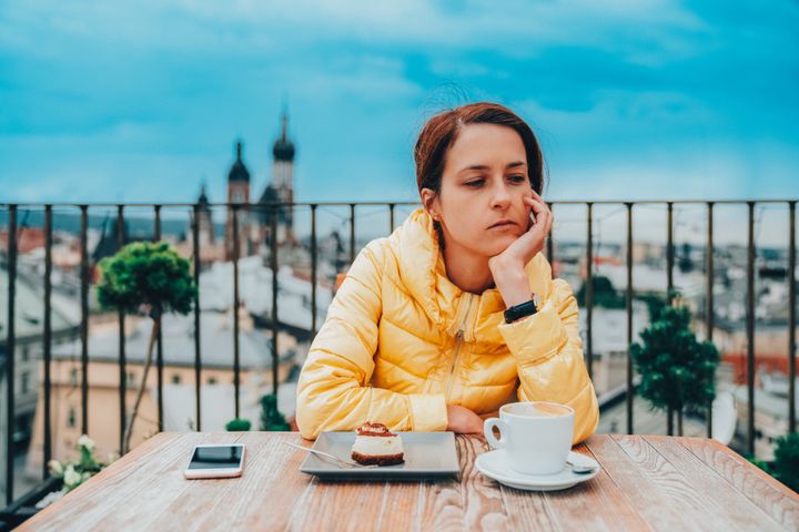 Depressed woman on the rooftop eating dessert with coffee