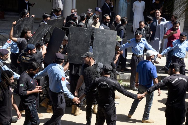 Private security personnel with bulletproof shields escort former Prime Minister Imran Khan as he arrives to appear in a court, in Islamabad, Pakistan, Tuesday, May 9, 2023. Officials from the party of Pakistan's former Prime Minister Khan say he has been arrested as he appeared in a court in the capital, Islamabad, to face charges in multiple graft cases.