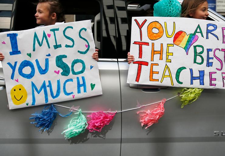 St. John School students hold signs as they drive by their teacher, Megan Congemi, during a surprise parade held in her honor on "Teacher Appreciation Day" in Boston on May 5, 2020. 