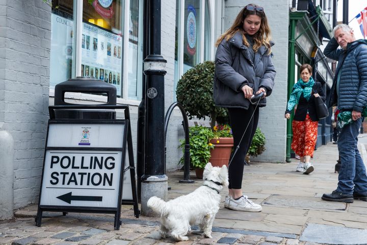 Voters leave a polling station with a dog on 4 May 2023 in Eton.