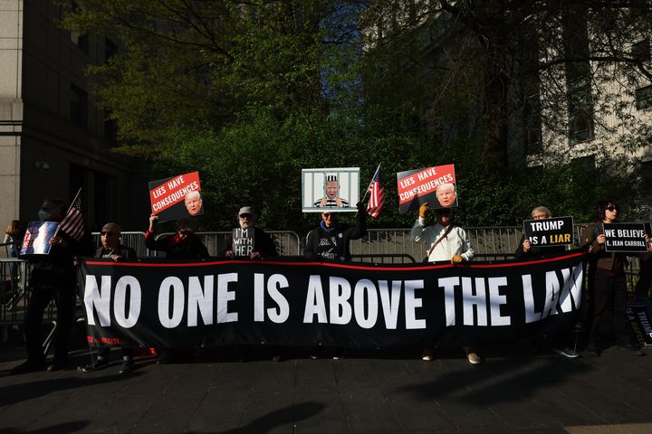キャロル氏の裁判が行われる法廷の外で「誰も法を超えることはできない」と書かれた旗を掲げる人々（2023年4月25日）