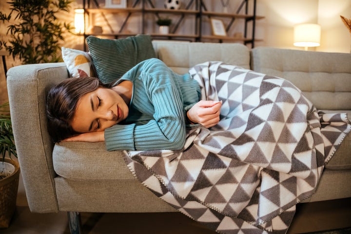 Tired young woman lying down in bed taking a rest at home.