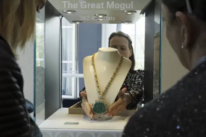 An employee of Christie's displays the Great Mogul Emerald and Diamond Necklace by Harry Winston during the preview of "The World of Heidi Horten." 