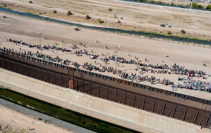 Migrants form lines outside the border fence in El Paso, Texas, on Wednesday as they wait for transportation to a U.S. Border Patrol facility.