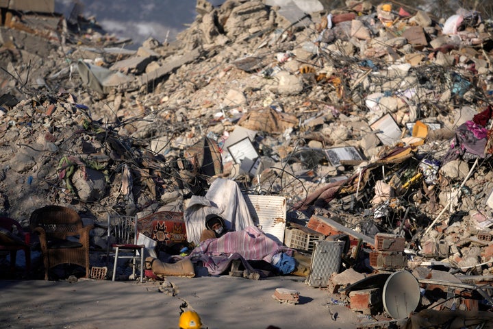 A man sleeps in front of a destroyed building in Kahramanmaras, southeastern Turkey, on Feb. 13, 2023. 