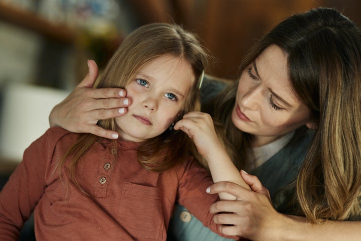 Young single mother taking care of her sad little daughter at home.