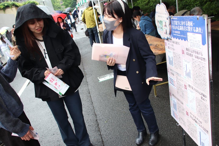 五月祭を訪れた人に調査結果について説明する川崎莉音さん（右）