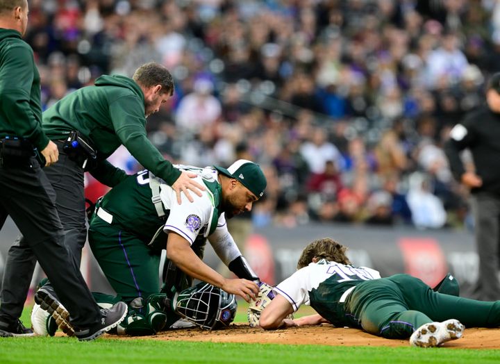 Colorado Rockies starting pitcher Ryan Feltner is assisted by Colorado Rockies catcher Elias Diaz and two trainers after Feltner was hit in the head on a line drive hit by Philadelphia Phillies right fielder Nick Castellanos.