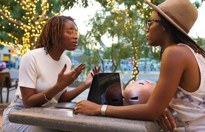 Black twin sisters discussing issues while sitting at a public park